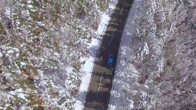 天线:蓝色的汽车在神奇的冰雪仙境的狭窄道路上超速行驶视频素材