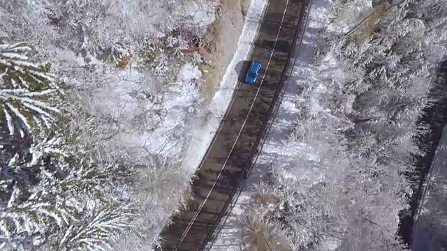 航拍图:一辆蓝色的汽车在冰雪皑皑的冬日里急转弯视频素材