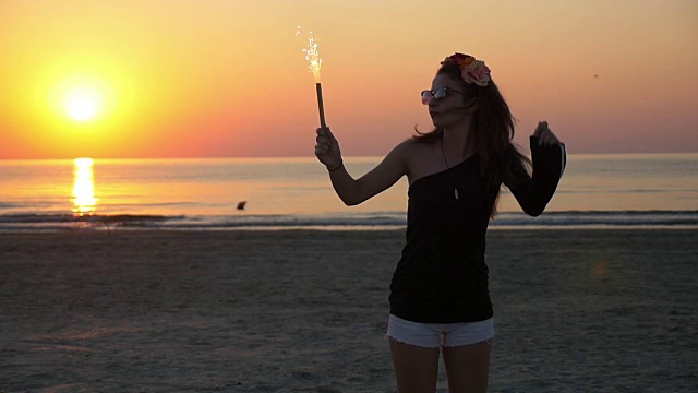 年轻美丽的少女女舞蹈在黄昏的海滩上与烟火蜡烛视频素材