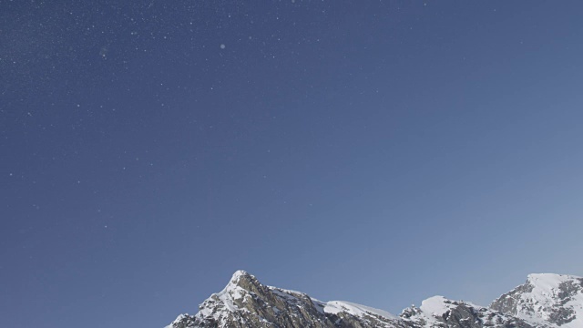 令人惊叹的雪花在雪山上方的冬日阳光下闪闪发光视频素材