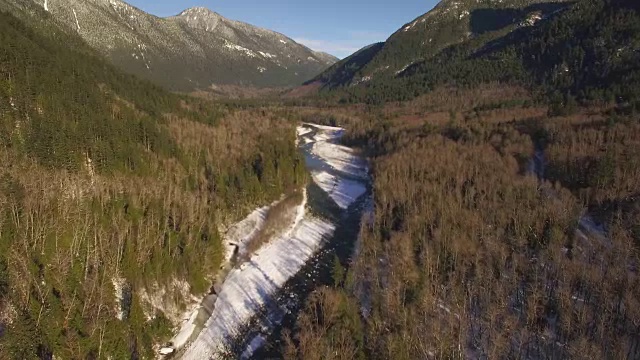 阳光明媚的一天冬季空中飞行的河流在太平洋西北山区森林山谷视频素材