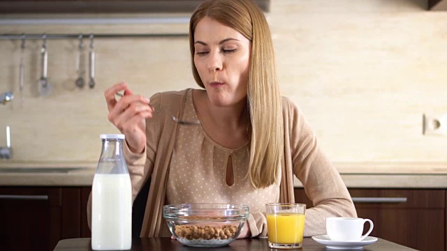 年轻漂亮的女人在厨房吃玉米片当早餐。一杯咖啡视频素材