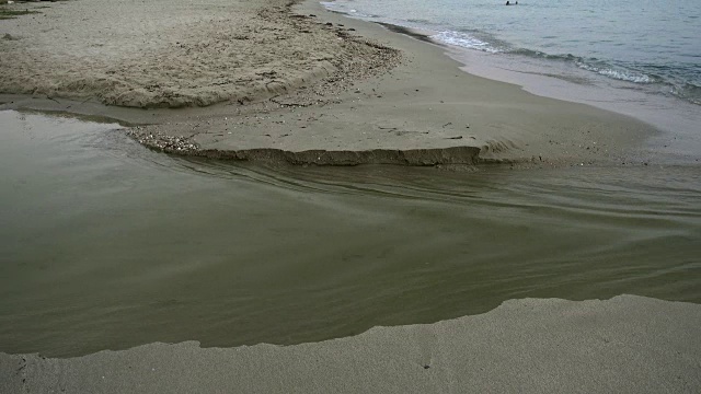 一对夫妇在一个河流流入大海的海滩上视频素材