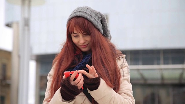 美丽的姜红色头发的女人使用智能手机技术应用程序在城市街道生活城市幸福的生活方式视频素材