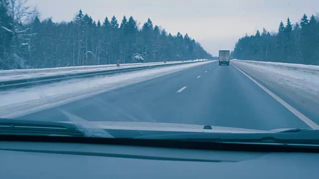 在白天冬天的路上开车。透过司机的挡风玻璃观看。视频素材