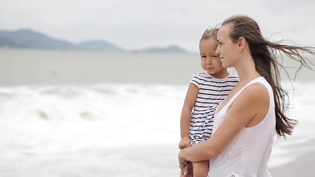 天气不好，妈妈带着小女儿在海滩上。视频素材