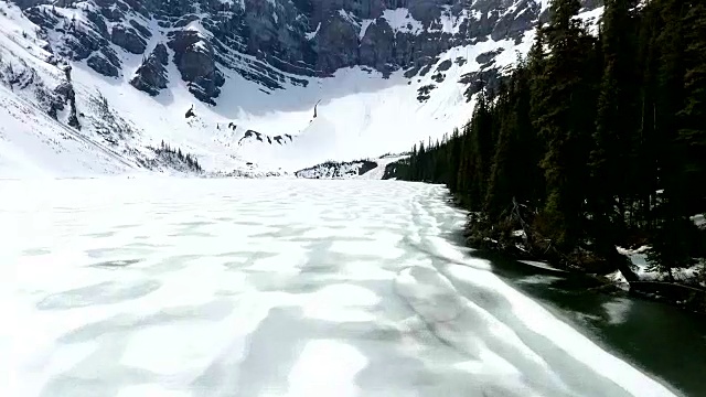 空中飞行:在有树的山上沿着结冰的湖飞行视频素材