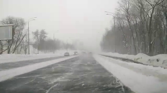 在雪地上驾驶POV。暴风雪驱赶城市街道的速度很快。冬季暴风雪来袭。在积雪和结冰的道路上危险的驾驶条件。视频素材