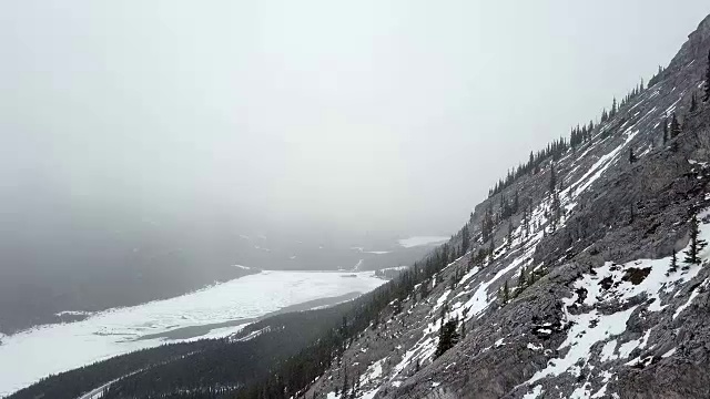 在暴风雪期间，空中飞过多雪的岩石山的边缘视频下载