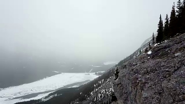 在暴风雪期间，空中飞过多雪的岩石山的边缘视频素材