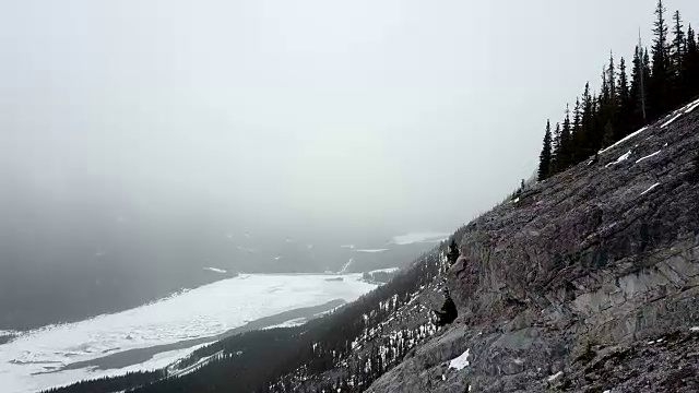 在暴风雪期间，空中飞过多雪的岩石山的边缘视频素材