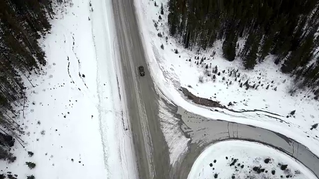 暴风雪期间，汽车在冬季山路上行驶时，架空俯仰视频素材