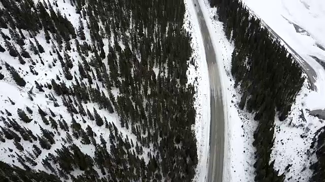 暴风雪期间，汽车在冬季山路上行驶时，架空俯仰视频素材