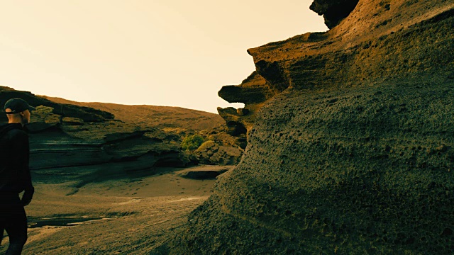 夕阳下，一个女人走在火山悬崖上视频素材