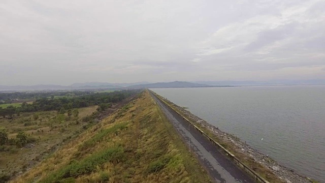 大坝与道路在边缘和山脉背景与无人机。视频素材