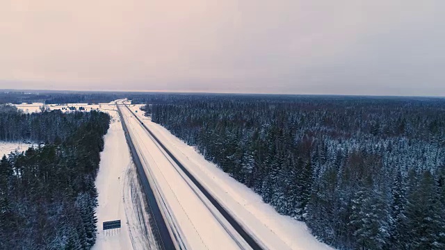 长长的道路上覆盖着厚厚的白雪，旁边是森林视频素材