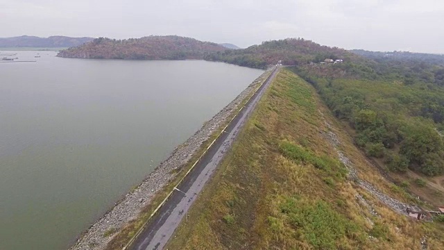 大坝与道路在边缘和山脉背景与无人机。视频素材