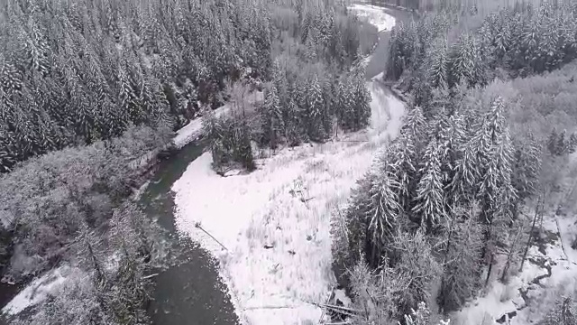 空中潘史诗般的冬季景观雪山森林与雪花落在冰冷的河流视频素材