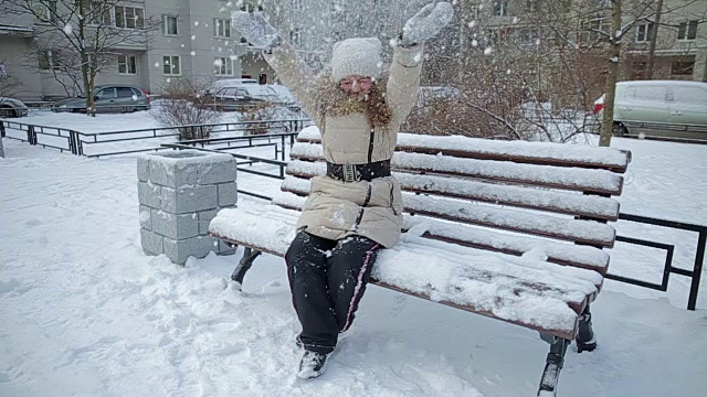 小女孩在长凳上下雪的慢动作视频素材