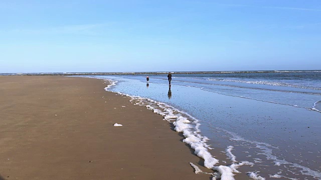 一家人在海边玩耍，海浪拍打着沙滩视频下载