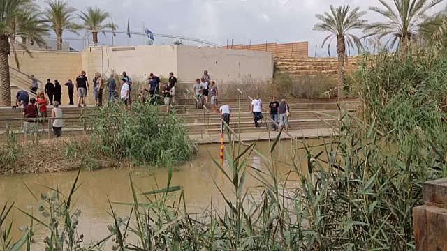 约旦河圣水附近的游客。拿撒勒人耶稣接受施洗约翰洗礼的地方。约旦和以色列之间的边界。视频素材