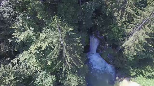 航拍图:山间的河流流过茂密的森林，从岩石上倾泻而下视频素材