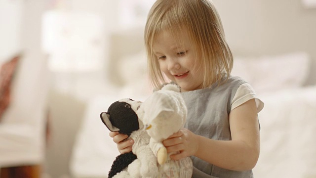 快乐的小女孩在她的房间里玩毛绒玩具。视频素材