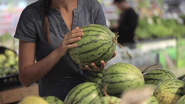 年轻漂亮的女人在超市挑选水果和蔬菜。视频素材