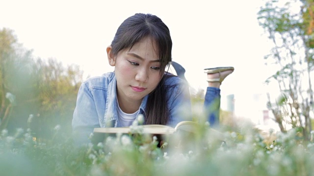 年轻的亚洲女孩在公园看书视频下载