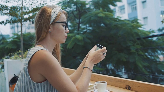 年轻漂亮的女商人在咖啡馆用智能手机工作。一名脸严肃的女性正在使用手机应用程序。视频素材