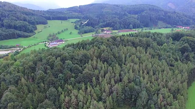 一架滑翔机飞越阿尔卑斯山森林，鸟瞰图视频素材