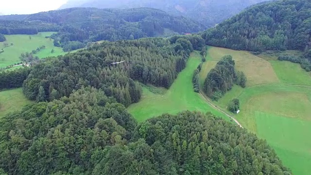 一架滑翔机飞越阿尔卑斯山森林，鸟瞰图视频下载