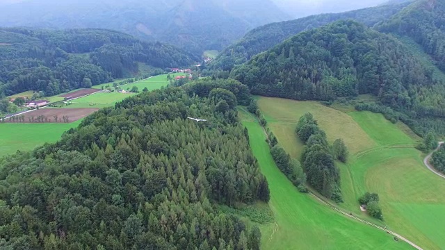 一架滑翔机飞越阿尔卑斯山森林，鸟瞰图视频下载