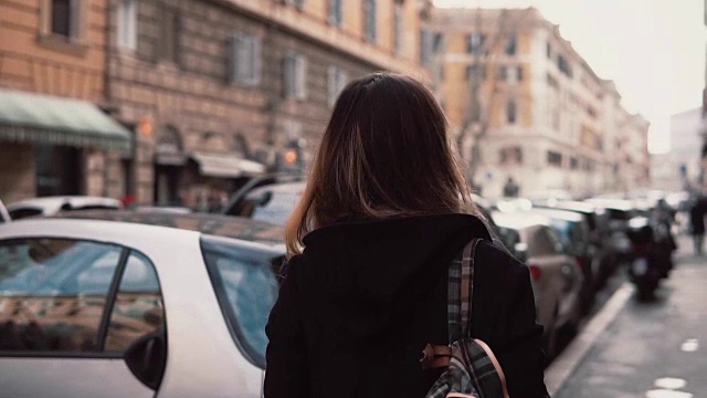 年轻女子在市中心行走并环顾四周的背影。黑发女孩背包探索新的地方视频素材