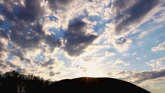 太阳照耀和去后面的山与云移动在时间推移视频视频素材