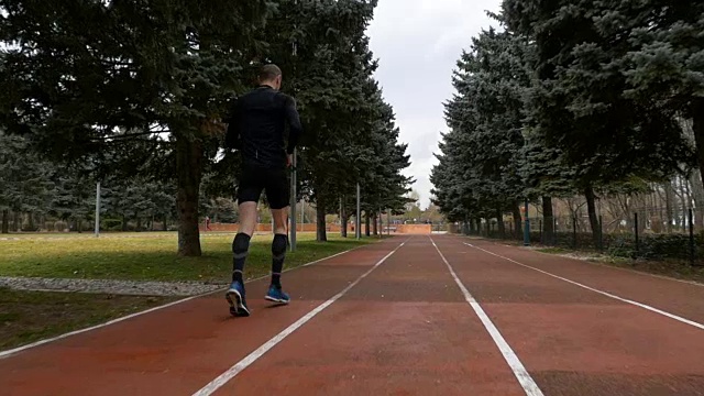 男人在跑道上慢动作慢跑的后视图视频素材