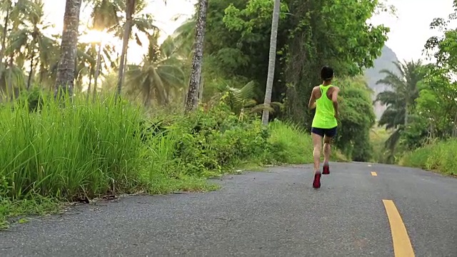 年轻的健身女子跑步早晨热带森林小径视频素材