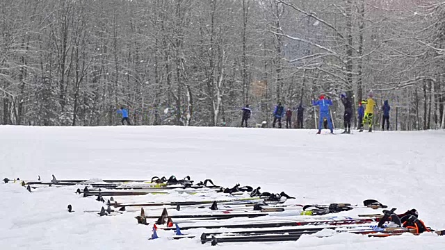 滑雪板和滑雪杖的设备都放在雪地上。年轻的滑雪者在白雪覆盖的草地上，在被森林包围的雪道上滑雪。活跃的冬季运动-越野滑雪在新鲜空气视频下载