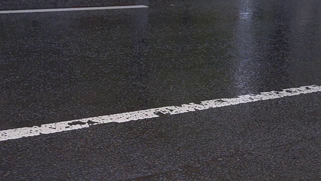 沥青路上下着大雨，车辆往来。视频素材