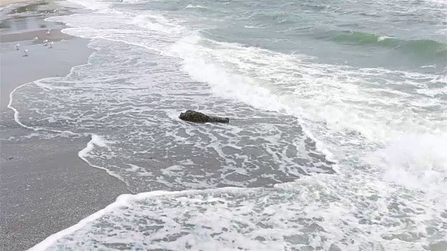 阴天海浪覆盖海滩上的石头，慢镜头，宽镜头视频素材