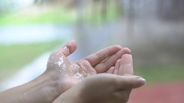 滴水在手。雨滴缓慢地落在一个女人的手上。视频素材