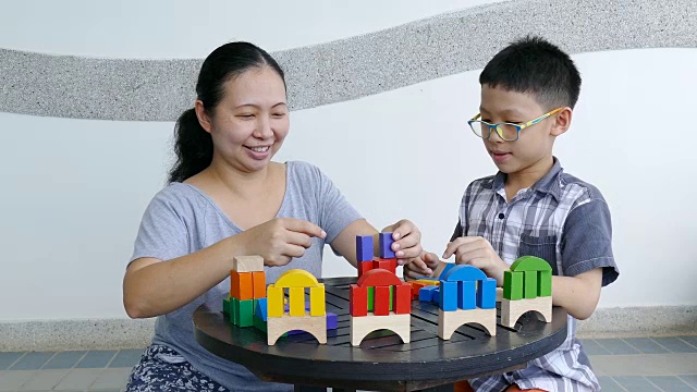 小男孩和妈妈在桌子上玩五颜六色的积木视频素材