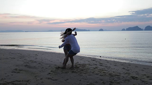 女人在海滩上跳在男人在日落，浪漫的夫妇游客愉快的会面视频素材