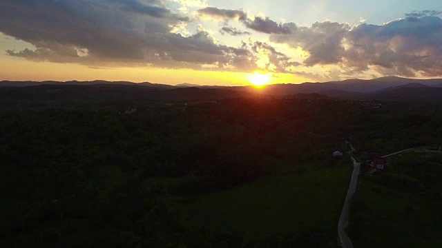 在夕阳的映衬下飞过绿色的山丘和村庄视频素材