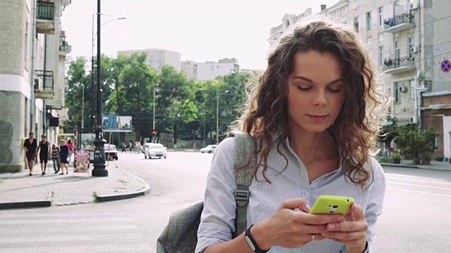 迷人的卷发女人在一个新的城市旅行，看手机上的地图视频素材