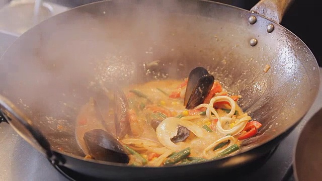 在街头美食节上，专业厨师正在用蔬菜煎贻贝和虾。烤虾和软体动物近距离。海鲜的烹调过程。传统的亚洲食物视频素材