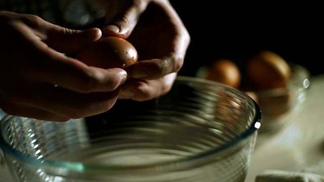 厨师手打鸡蛋。男性手破卵。准备食物视频素材