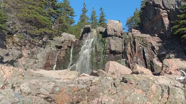 近距离观察:山泉跌落在荒野的火山岩石苔藓墙上视频素材