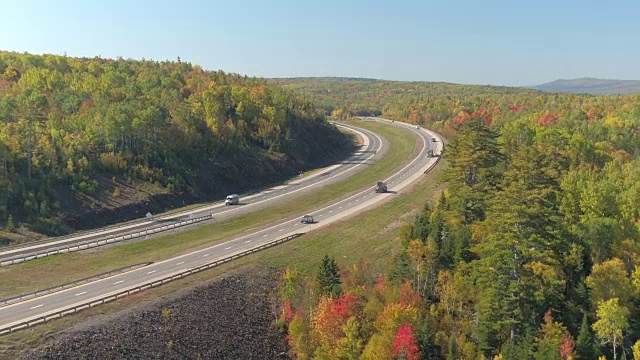 空中风景繁忙的公路在阳光明媚的日子蜿蜒穿过丘陵森林景观视频素材