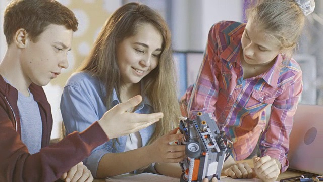 两个女孩和一个男孩在科学课的机器人项目中工作。视频素材